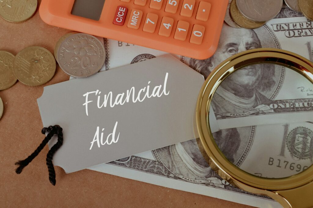 Magnifying glass, calculator and money with text FINANCIAL AID.